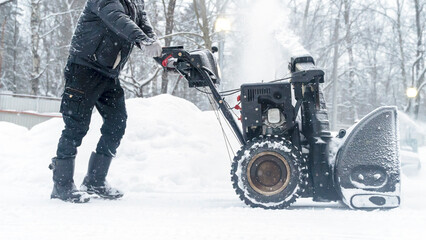 a janitor on a snowplow removes snow in the courtyard of a residential building
