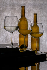 Still life with books, empty bottles and glasses with liquid