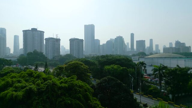 Drone view of trees with misty Jakarta cityscape