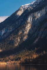 Landscape of Snowy Mountains Alps by lake in Hallstatt, Austria with blue sky, vertical shot