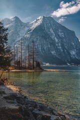 Landscape of Snowy Mountains Alps by lake coast in Hallstatt, Austria with blue sky, vertical shot