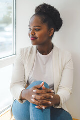 African woman relaxing in the cafe near the office looking out the window. Enjoying leisure time. Work break.