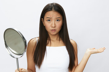 Asian woman with mirror in hand facial skin problems, acne and inflammation, red rash and...