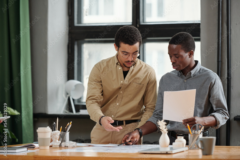 Poster Confident African American businessman pointing at document while explaining data to colleague during presentation of project plan