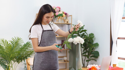 Florist concept, Female florist cut chrysanthemum stem with scissor for make flower bouquet at shop