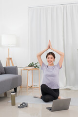 Fototapeta na wymiar Yoga exercise concept, Asian woman raising arms over head in lotus position while doing yoga online