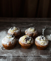 muffins with custard, berries and powdered sugar on a wooden table