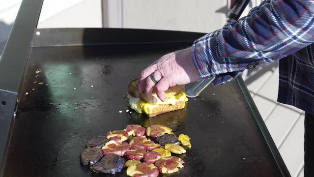 Plating the grilled Texas toast and egg sandwich after grilling it on the flat top griddle with smash potatoes