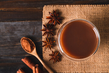 Hot cocoa in cup glass with cinnamon stick, star anise and cocoa powder on wooden background, Hot drink in winter season, Table top view