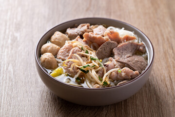 Rice noodles soup with pork in bowl on wooden background, Asian food