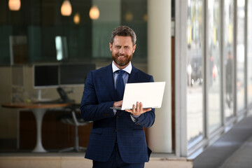 Businessman with notebook outdoor. Confident business expert. Handsome man in suit holding laptop against office background.