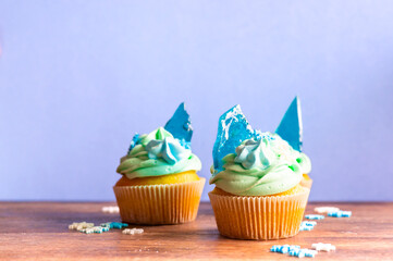 Homemade cupcake of blue color placed on wooden desk. Winter and christmas theme, snowflakes on...