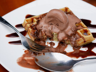 Chocolate waffle already sliced with ice cream topping on a plate