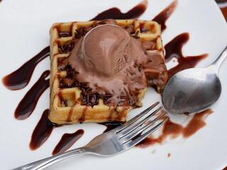 Chocolate waffle already sliced with ice cream topping on a plate