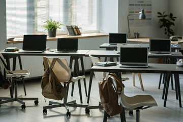 Modern empty classroom with computers on desks for IT lesson