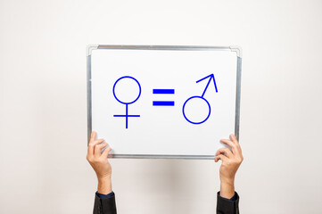 Zwei Hände halten eine Tafel hoch auf der ein Symbol für männlich und weiblich zu sehen sind mit...