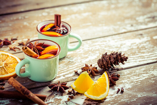 Mulled wine in rustic mugs with spices and citrus fruit