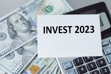 Invest 2023 text on a card, calculator and dollors