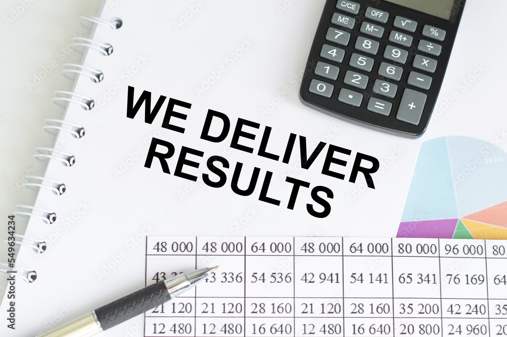 Poster we deliver results text on notepad on the table next to calculator, pen and documents