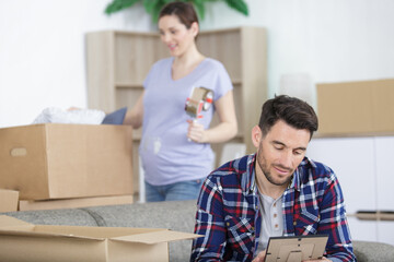 happy pregnant couple with belongings at new home