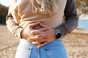 A young man hugs a girl in jeans and a sweater around the waist, fingers crossed on her back. Close-up of hands