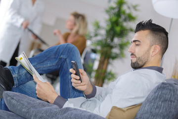 man using smartphone while sat in medical waiting room