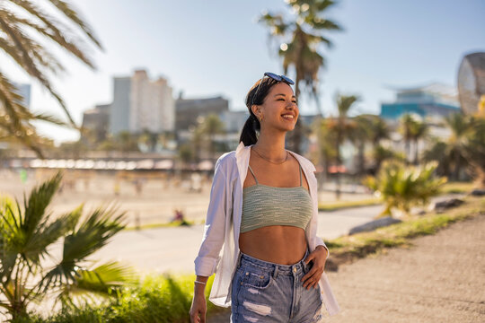 Smiling young asian woman posing and smiling near the beachport
