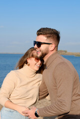 Fototapeta premium A bearded young man in sunglasses hugs a girl by the waist. couple laughing happily