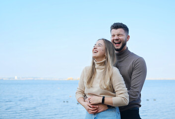 Beautiful young married couple posing on the beach. Man and woman laughing and hugging