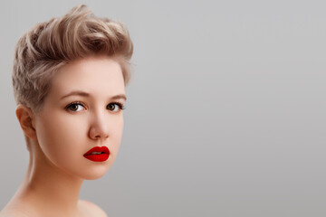 High fashion look . glamor closeup portrait of beautiful sexy blond Caucasian young woman model with red lips ,bright makeup , with short hair with perfect clean skin isolated gray