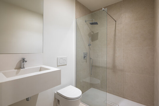 Empty Interior of modern white bathroom with mirror, sink, toilet and shower with glass partition