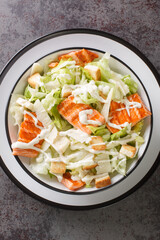 Salmon Caesar Salad it features easy homemade dressing, freshly baked croutons, parmesan and grilled salmon closeup on the plate on the table. Vertical top view from above