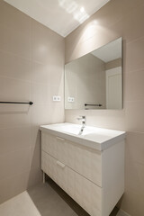 Simple, empty and modern bathroom with beige tiles, sink and mirror