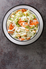 Delicious light salmon caesar salad with fresh croutons, lettuce and grilled fish close-up in a plate on the table. Vertical top view from above