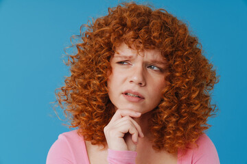 European woman with red curly hair frowning and looking aside