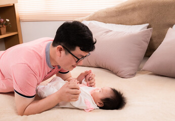 Asian father sing or talk with adorable daughter on bed, close up dad eye contact with healthy...