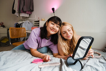 Two multiracial girls smiling and doing makeup at home