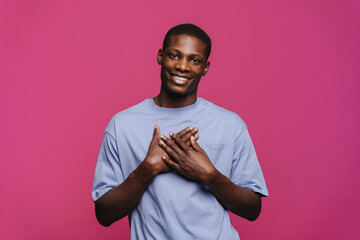 Black young man smiling and holding hands on his chest
