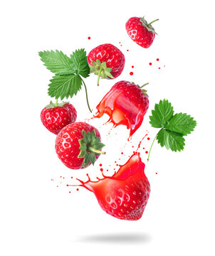 Whole and sliced strawberries with juice splashes in the air isolated on a white background