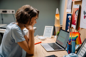 Young white woman working with laptop while sitting at desk