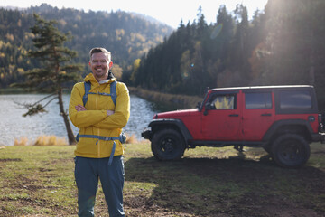 Happy smiling male tourist standing near mountain lake © megaflopp