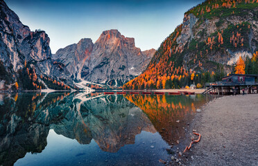 Superb autumn view of Braies (Pragser Wildsee) lake with boats and fishing dock. Magnificent dawn in Fanes-Sennes-Braies national park, Dolomite Alps, South Tyrol, Italy. Traveling concept background.