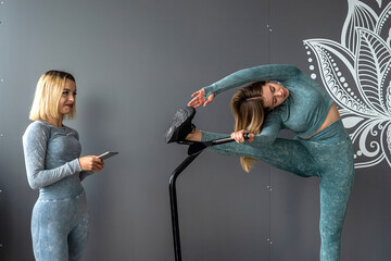 beautiful young girl trainer shows how to train correctly on a fitness trampoline in the gym.