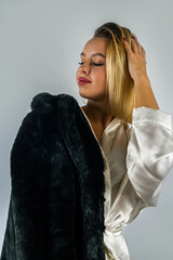 young beautiful blonde in a white silk robe with a fur coat on top.