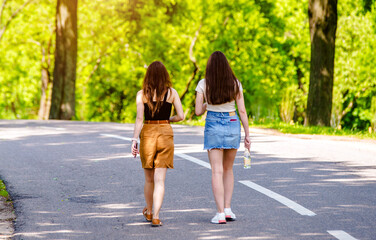 Obraz premium Two girlfriends walk along a path in the Park 