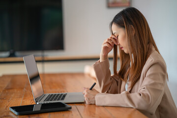 Asian women are stressed while working on laptops, Tired Asian businesswomen with headaches at the office, feel sick at work, and copy space.