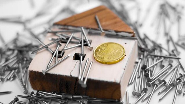 Wooden cracked house with a coin and falling metallic nails in slow motion. Property renovation and insurance idea. Conceptual miniature