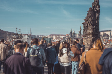 Multitude of people on charles bridge in prague, with the view towards the famous hradcani hill on a crowded autumn day.