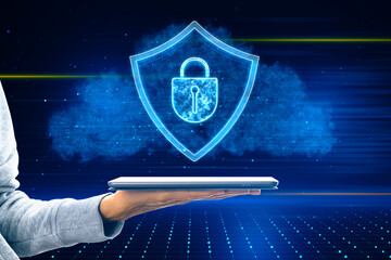 Close up of female hand holding tablet glowing shield hologram on blurry background. Secure,...