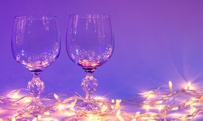Two wine glasses and a garland in neon lighting, Valentines day background.